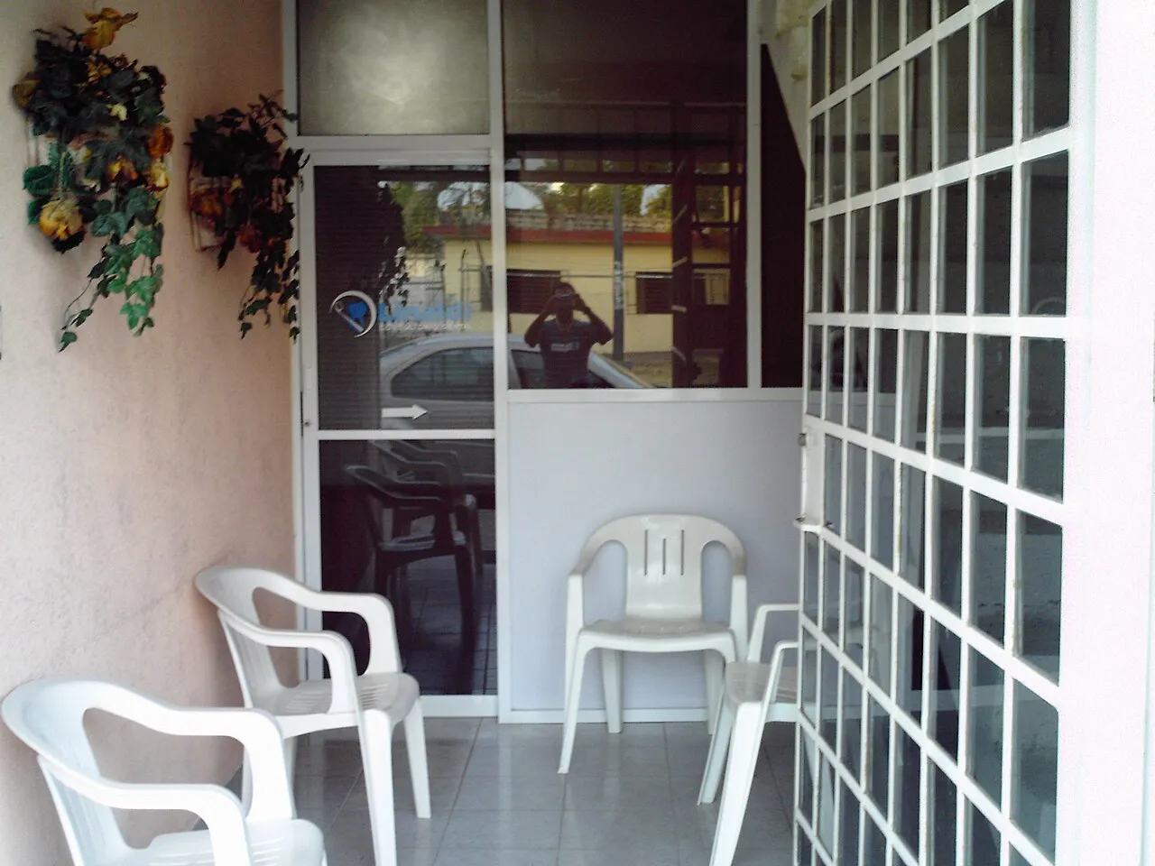 Sala de espera de un consultorio dental con sillas blancas de plástico junto a un muro de vitroblock